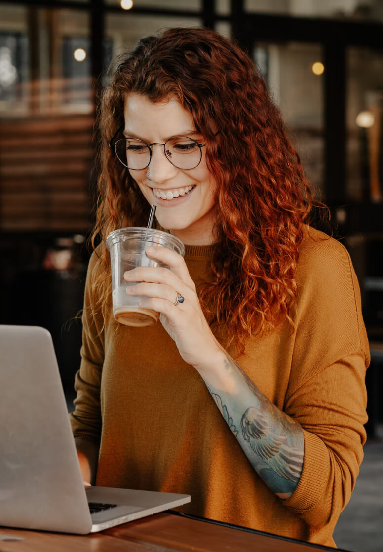 Image of a woman smiling and enjoying her coffee.